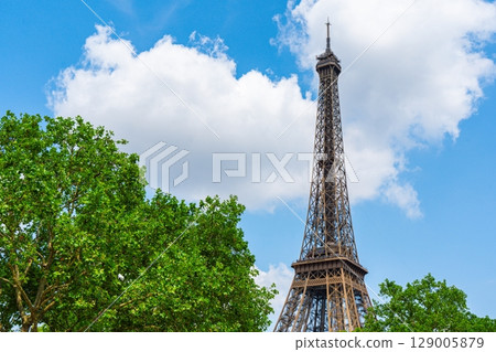Eiffel Tower Ascending into a Blue Sky A Parisian Landmark Amongst Green Trees. Eiffel Tower Ascending into a Blue Sky A Parisian Landmark Amongst Green Trees. 129005879