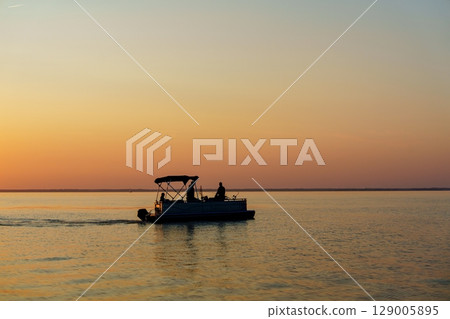 Sunset Fishing Trip Pontoon Boat Silhouette on the Baltic Sea at Dusk, Serene Waters Sunset Fishing Trip Pontoon Boat Silhouette on the Baltic Sea at Dusk, Serene Waters 129005895