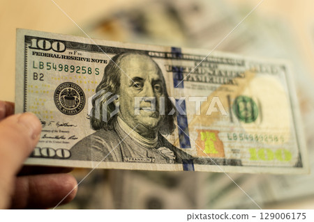 In hand is a 100 dollar bill 129006175