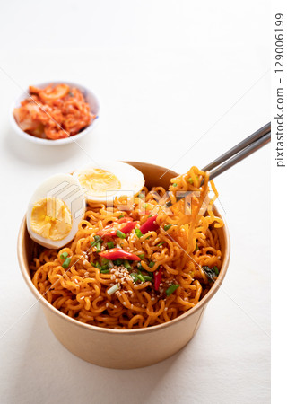 Spicy Korean dried instant noodles with boiled egg in kraft paper bowl and kimchi cabbage Spicy Korean dried instant noodles with boiled egg in kraft paper bowl and kimchi cabbage 129006199