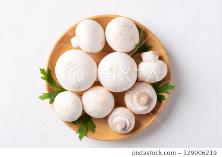 White Button mushroom or Champignon mushroom (Agaricus bisporus) on wooden plate 129006219