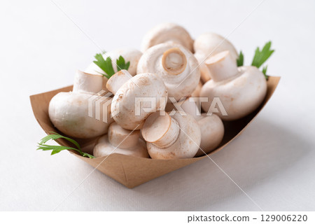 White Button mushroom or Champignon mushroom (Agaricus bisporus) in paper bowl, Food ingredient White Button mushroom or Champignon mushroom (Agaricus bisporus) in paper bowl, Food ingredient 129006220