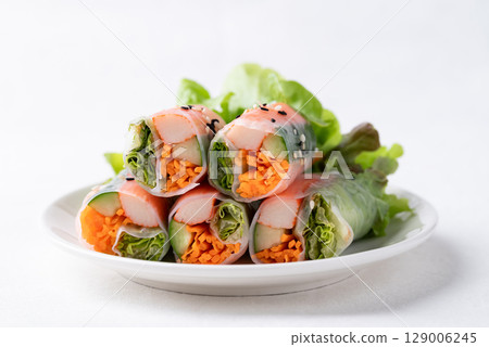 Salad roll with crab stick, carrot, cucumber and lettuce wrapped with rice paper on dish 129006245