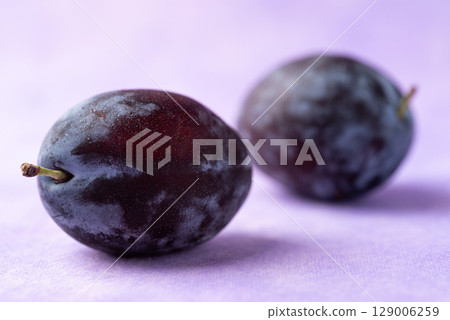 Fresh blue plum fruit on purple background Fresh blue plum fruit on purple background 129006259