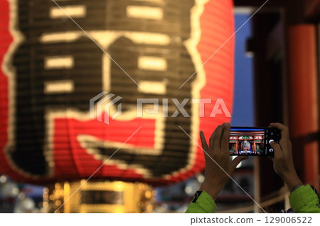A smartphone taking pictures of Kaminarimon at night; Foreign tourists taking pictures of the giant lantern 129006522