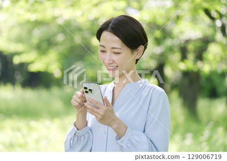 A woman in her 40s using a smartphone outdoors A woman in her 40s using a smartphone outdoors 129006719