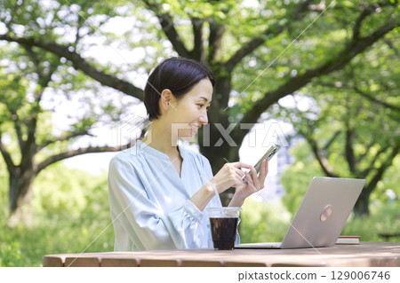 戶外使用智慧型手機和筆記型電腦的女性 129006746