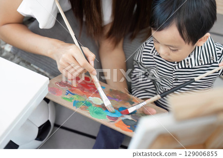 Collaborative art. Mother and child painting together with joy. 129006855