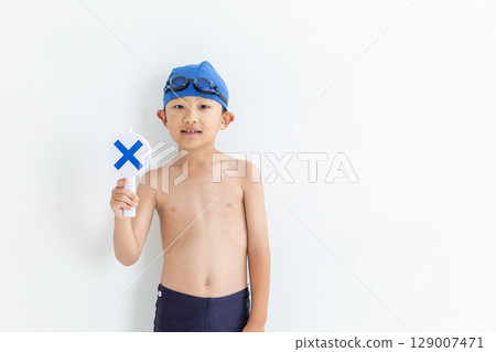 A boy in a swimsuit holding a cross sign 129007471