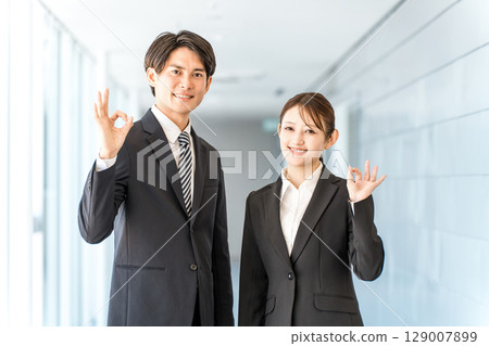 Young Asian businessmen and women in suits standing in the office corridor (ok, recommended, success) Young Asian businessmen and women in suits standing in the office corridor (ok, recommended, success) 129007899