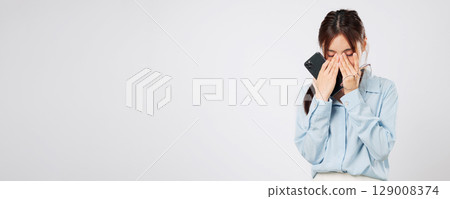 Vision problem Young Asian woman rubbing eyes from fatigue, vision blurred after using glasses, stress and pain showing eye discomfort with tired hands. isolated studio white background Vision problem Young Asian woman rubbing eyes from fatigue, vision blurred after using glasses, stress and pain showing eye discomfort with tired hands. isolated studio white background 129008374