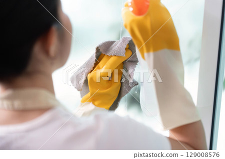 Home Cleaning. Woman using cloth to clean window with precision. Home Cleaning. Woman using cloth to clean window with precision. 129008576