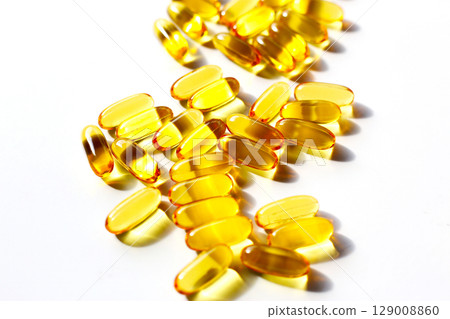 Golden fish oil capsules on white background. 129008860