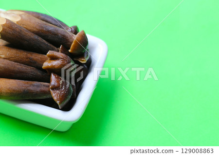Termite mushrooms with long stems, white tips, and dark brown caps. 129008863