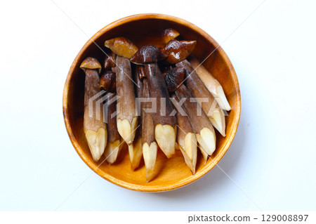 Termite mushrooms with long stems, white tips, and dark brown caps. 129008897