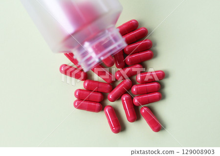 Red astaxanthin supplement capsules on a white background. 129008903