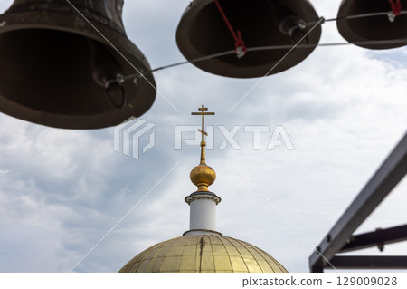 Golden Church Dome and Cross Beneath Historic Clock Bells 129009028