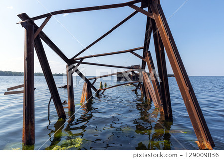 Rusty Metal Bridge Structure Partially Submerged in Tranquil Waters 129009036