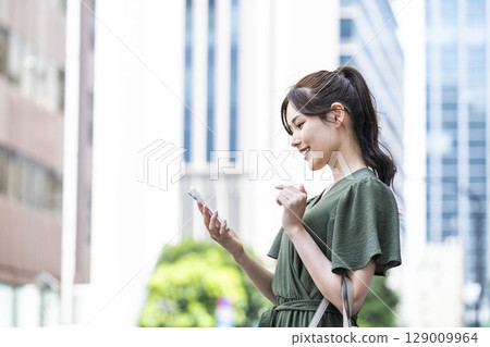 一名年輕女子在辦公區操作智慧型手機 一名年輕女子在辦公區操作智慧型手機 129009964