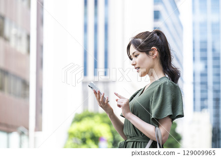 A young woman operating a smartphone in an office area A young woman operating a smartphone in an office area 129009965