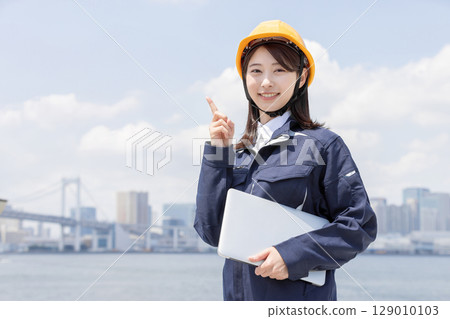 一位身穿工作服的年輕女子指著 一位身穿工作服的年輕女子指著 129010103