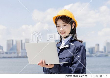 穿著工作服的年輕女子正在使用筆記型電腦 129010104