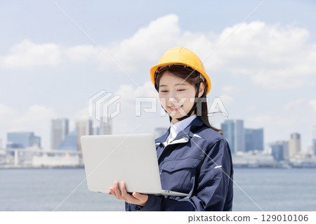 穿著工作服的年輕女子正在使用筆記型電腦 129010106
