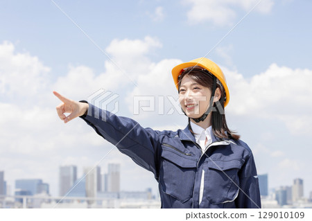 A young woman in work clothes pointing 129010109