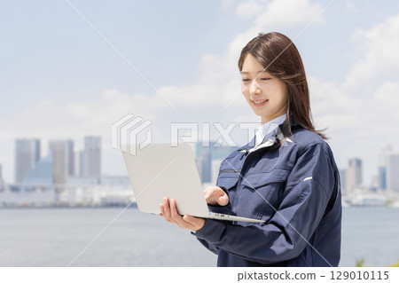 一位身著工作服的年輕女子在筆記型電腦上搜尋(建築、施工、土木工程、物流、工業) 一位身著工作服的年輕女子在筆記型電腦上搜尋(建築、施工、土木工程、物流、工業) 129010115