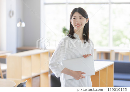 Businesswoman holding a laptop in a shared office Businesswoman holding a laptop in a shared office 129010155