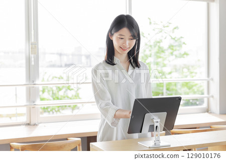 飯店接待處的年輕女性，使用平板電腦，自助辦理入住 129010176