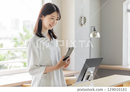 Young woman at hotel reception, tablet, self check-in Young woman at hotel reception, tablet, self check-in 129010181
