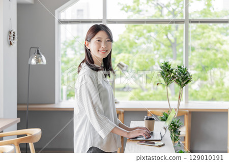 Woman using laptop while standing in coworking space Woman using laptop while standing in coworking space 129010191