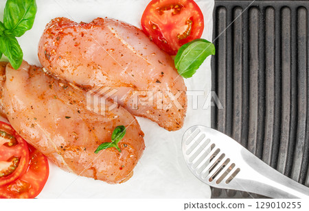 Raw marinated chicken breasts with tomatoes and basil ready for grilling. top view. copy space 129010255