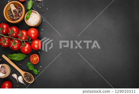 Fresh tomatoes, herbs, garlic, and spices arranged on black background with copy space. top view. Fresh tomatoes, herbs, garlic, and spices arranged on black background with copy space. top view. 129010311