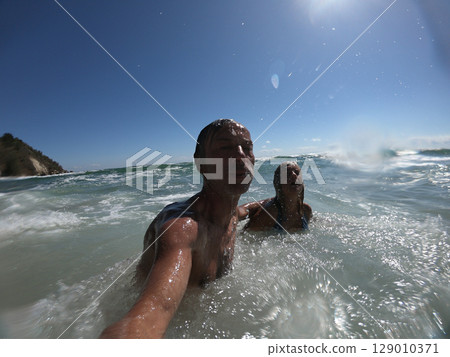 Powerful ocean waves splashing funny couple 129010371