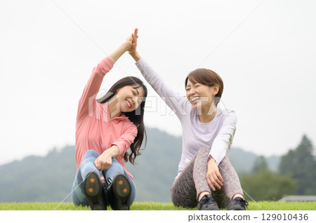 Two women high-fiving after exercise 129010436