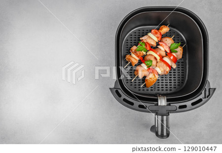 Raw chicken skewers with vegetables in an air fryer basket, ready for cooking. copy space, top view 129010447