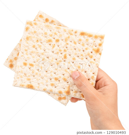 Hand holding traditional matzo crackers, a symbolic food in Jewish culture, isolated on white background 129010493