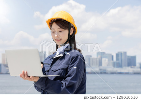 A young woman in work clothes using a laptop A young woman in work clothes using a laptop 129010510