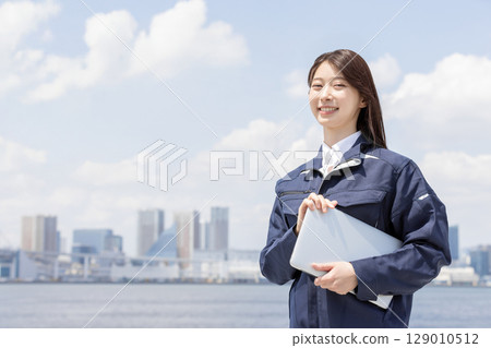 身穿工作服的年輕女子抬頭仰望（建築、施工、土木工程、物流、工業） 129010512