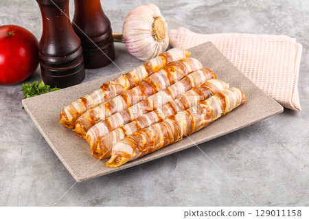 Raw sausages wrapped in bacon Raw sausages wrapped in bacon 129011158