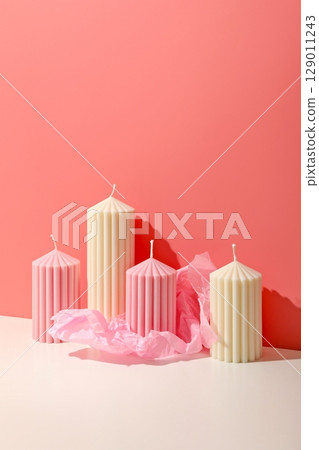 Ribbed candles in shades of pink and cream on a light surface 129011243