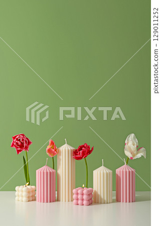 Candles in various shapes and colors are complemented by fresh flowers 129011252