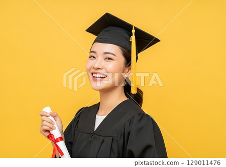 Radiant Asian Graduate Beaming with Pride Holding Diploma on Yellow Background. Radiant Asian Graduate Beaming with Pride Holding Diploma on Yellow Background. 129011476