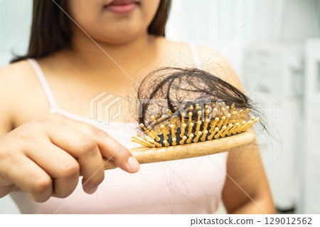 Asian woman have problem with long hair loss attach to comb brush. 129012562