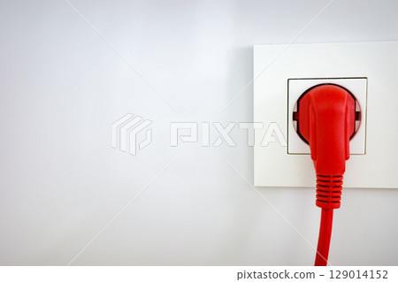 Red power plug connected to a wall socket 129014152
