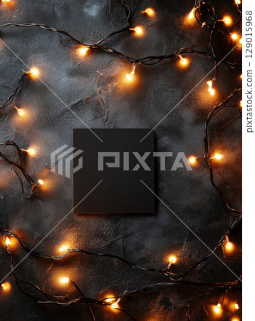 Festive String Lights Surrounding a Minimalist Black Canvas on Dark Background 129015968