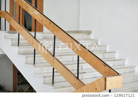 A flight of stairs with marble steps. Whitewashed walls and wooden staircase railings. The staircase of an old building. A flight of stairs with marble steps. Whitewashed walls and wooden staircase railings. The staircase of an old building. 129017121