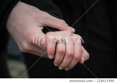 Love and affection concept. Male and female hand with silver ring together Love and affection concept. Male and female hand with silver ring together 129017498